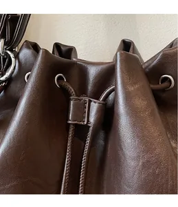 Detail of dark brown drawstring bucket bag with litchi grain leather and silver ring hardware