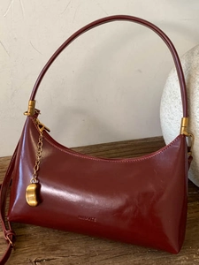 Elegant burgundy leather hobo underarm bag with gold accents on a wooden surface