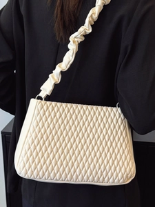 Minimalist cream white quilted shoulder bag with unique pleated strap shown on model