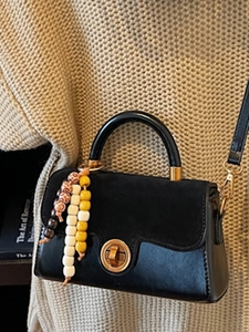 Retro black mini handbag with gold clasp and colorful beaded charm on beige knit sweater