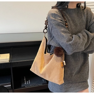 Détail d'un sac cabas en daim kaki avec anse en perles de bois et breloque en peluche