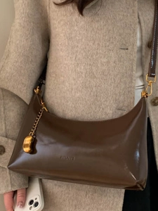 Retro dark brown glossy hobo bag with gold hardware worn with a beige wool coat