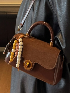 Vintage brown leather crossbody bag with beaded charm and gold clasp shown on model