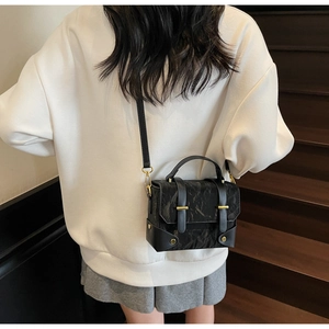 Détails d'un sac messager noir en cuir froissé avec des garnitures dorées