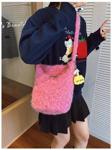 Detail of pink plush bucket bag with long strap and heart-shaped pendant accessory