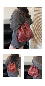 Detail view of a vintage red drawstring bucket bag with silver metal ring and chain charm