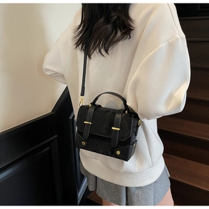 Vue détaillée d'un sac messager noir rétro avec garniture dorée porté par un mannequin