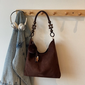 Détail du sac cabas en daim marron avec perles en bois et breloque en forme de pompon