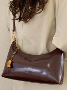 Retro dark brown patent leather hobo bag with gold hardware worn with a beige trench coat