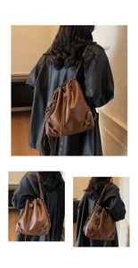 Detailed view of the drawstring closure and woven tassel on the brown leather bucket bag