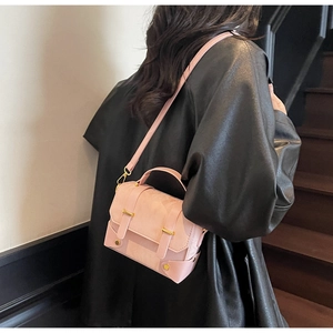 Détail du sac à main rose structuré avec poignée et boucle en métal doré sur modèle