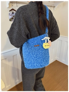 Detail of blue plush bucket bag with Star picking leather tag and yellow flower charm
