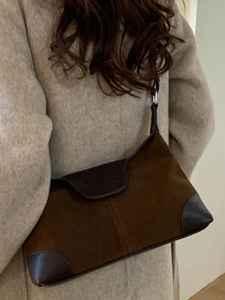Borsa a spalla retrò in pelle scamosciata marrone indossata con un cappotto di lana beige elegante