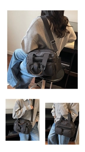 Detailed view of black nylon crossbody bag with multi-pocket design and wide fabric strap