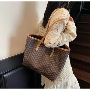 Detailed view of dark brown monogram tote bag with tan leather straps and trim on a model