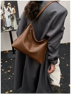 Detail view of the brown leather hobo bag with sleek finish and logo tag on a shoulder strap