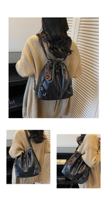 Detail view of black drawstring bucket bag with silver hardware and woven ring charm