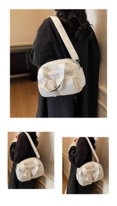Detail view of a white nylon shoulder bag featuring multiple functional front zipper pockets