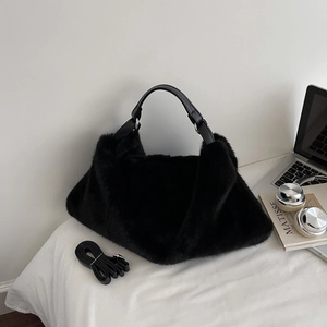 Gros plan d'un sac cabas en fausse fourrure noire avec poignée en cuir lisse et décor