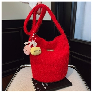 Detail of red plush bucket bag featuring soft mohair texture and cute cherry pendant accessory