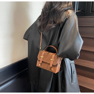 Détail du sac bandoulière vintage marron avec texture plissée brillante et boucles dorées