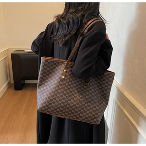 Close-up of brown tote bag with NK monogram pattern and sturdy synthetic leather handles