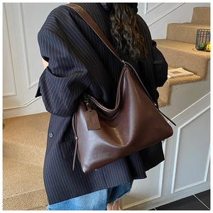 Detail view of deep brown large tote bag in soft leather with a minimalist shoulder strap