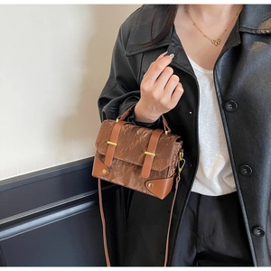 Détail du sac en similicuir marron avec texture plissée vintage et garnitures dorées