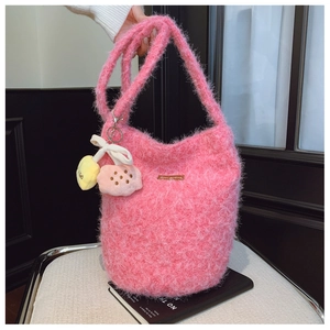 Close-up of pink fluffy bucket bag with cute plush cloud charms and branded label