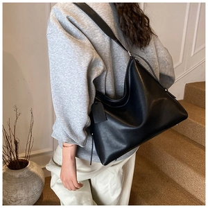 Detail of a large black matte leather tote bag with wide strap for stylish commuting