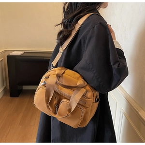 Detail of yellow nylon shoulder bag with multiple functional pockets and adjustable strap