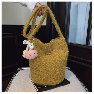 Detail of yellow fuzzy plush bucket bag featuring Star-picking leather tag and bow charm
