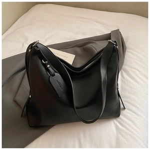 Close-up of black PU leather tote bag with embossed brand tag and premium texture
