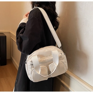 Detail view of a white multi-pocket nylon crossbody bag with adjustable wide strap