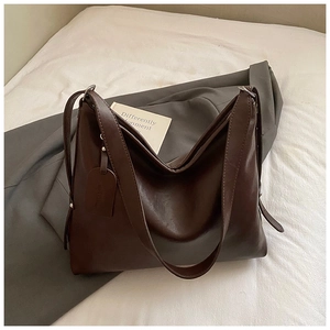 Detail of deep brown glossy leather tote bag showing smooth texture and hanging tag