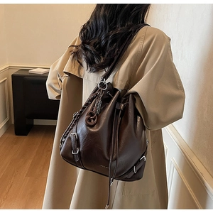 Detailed view of deep brown bucket bag with drawstring closure and silver hardware on a model