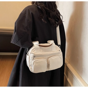 Close-up of cream nylon crossbody bag featuring dual front pockets and brown leather handles