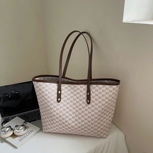 Detail view of large tote bag with NK pattern, laptop, and headphones in office setting