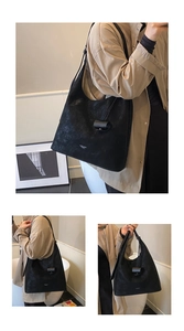 Detail view of large black matte leather hobo bag with unique cylindrical strap ornament