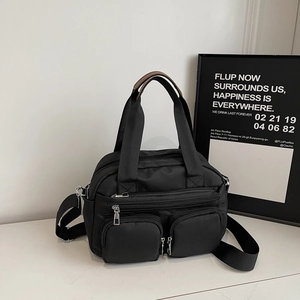 Detail view of the multi-pocket nylon bag with top handles and adjustable shoulder strap