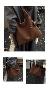 Detail of dark brown leather tote bag with white logo and matching pendant accessory