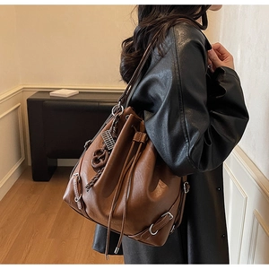 Detail of dark brown leather bucket bag showing drawstring closure and silver hardware