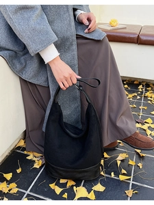 Detail of black suede and leather crescent shoulder bag with minimalist design features