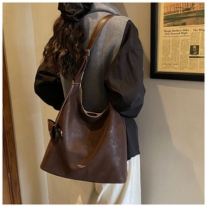 Detail of vintage brown leather tote bag with gold lettering and textured finish