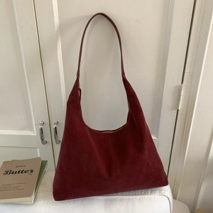 Detailed close-up of dark red suede hobo bag with high-quality stitching and texture