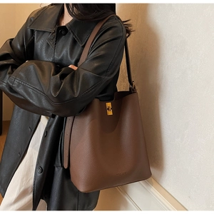 Détail du sac cabas en cuir marron grainé avec fermoir rotatif doré et bandoulière large