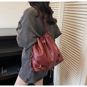 Detail view of burgundy leather drawstring bucket bag worn as a shoulder pack