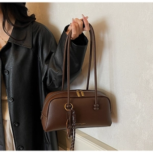 Close-up of brown litchi pattern leather pillow bag with double zippers and gold hardware