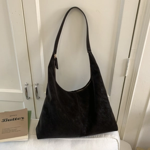 Detail view of the black faux suede hobo bag with top metal zipper and minimalist finish