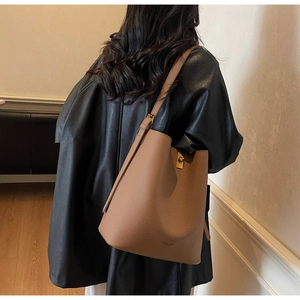 Détail du sac seau en cuir grainé avec boucle en métal doré et bandoulière réglable